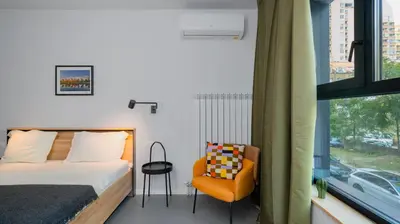 a bedroom with a bed and a chair and a window at Aviva City Stay by Flat Mаnager in Sofia