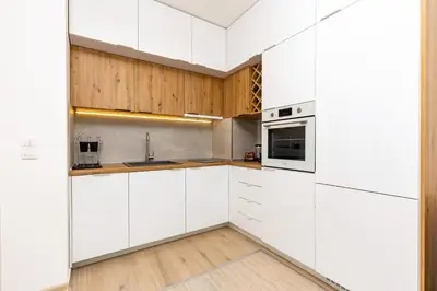 a white kitchen with wooden cabinets and a sink at Magnolia Gardens -1BD with Balcony & Parking by Flat Mаnager in Plovdiv