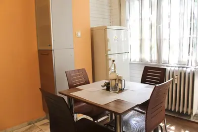 a dining room table with chairs and a refrigerator at Apartment Near NDK Biairbnb in Sofia