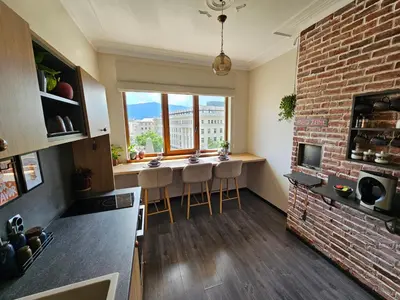 a kitchen with a brick wall and a bar with stools at S íRMA Apartment - Amazing View of the Golden Domes in Sofia