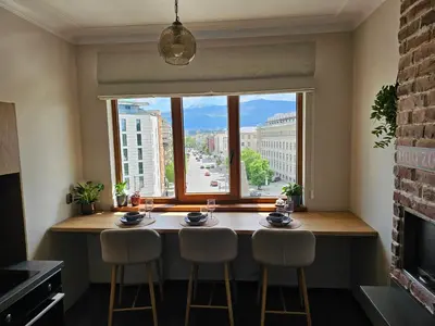 a dining room table with two chairs and a large window at S íRMA Apartment - Amazing View of the Golden Domes in Sofia