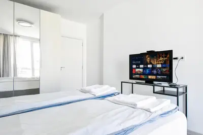 a white room with two beds and a flat screen tv at Crème Lux - Elegant 1BD in Manastirski Livadi by Flat Manager in Sofia
