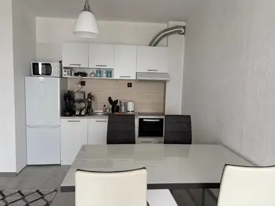 a kitchen with white cabinets and a table and chairs at Трушеви in Sandanski