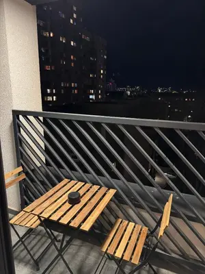 a wooden table and chairs on a balcony at night at Stylish Apartment in City Center in Sofia