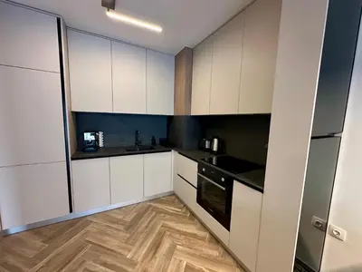 a kitchen with white cabinets and a wooden floor at Milea apartments in Sofia