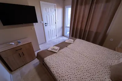 a bedroom with a bed and a flat screen tv at Къща за гости Катлея in Hisarya