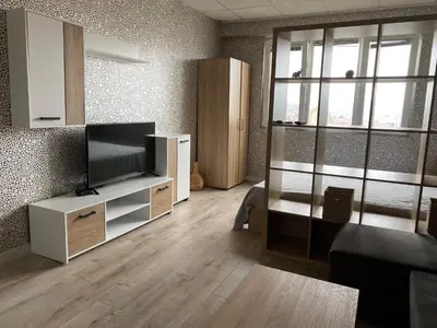 a living room with a flat screen tv on a cabinet at Панорама in Panagyurishte