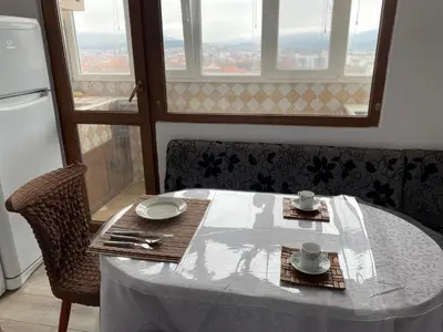 a table with a white tablecloth on a table with a window at Панорама in Panagyurishte
