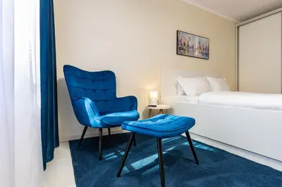 a bedroom with a blue chair and a bed at Central Chic 1BD Apt Near Kapana by Flat Manager in Plovdiv