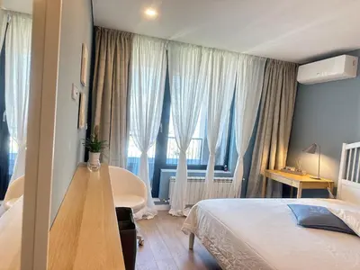 a bedroom with a bed and a large window at Апартамент В 48 в Сграда МОНА in Sofia