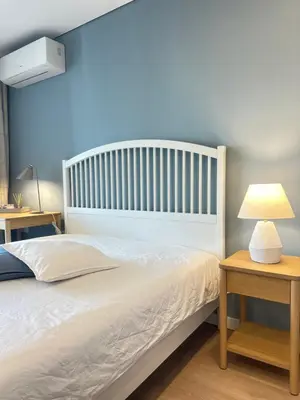 a bedroom with a white bed and a table with a lamp at Апартамент В 48 в Сграда МОНА in Sofia