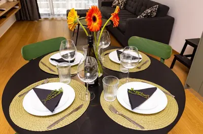 a black table with plates and wine glasses and flowers at Stylish apt 'Photo Booth' with an amazing location in Plovdiv