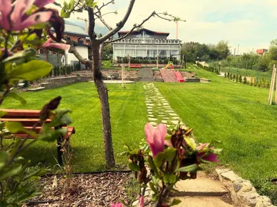a park with a building in the background with pink flowers at Villa YoSi in Sapareva Banya