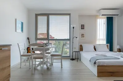 a bedroom with a bed and a table and chairs at Студио 9 Парк Панорама in Hisarya
