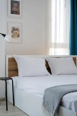 a bed with white sheets and pillows in a bedroom at Студио 9 Парк Панорама in Hisarya