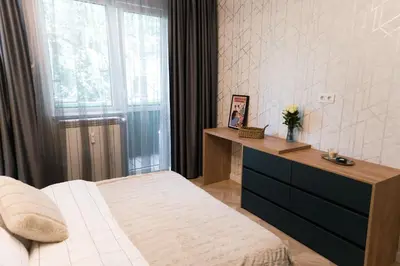 a bedroom with a bed and a dresser with a window at Луксозен арт апартамент в близост до центъра на града in Sofia