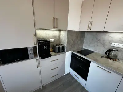 a kitchen with white cabinets and a black appliance at Apartment Aria 6 in Velingrad