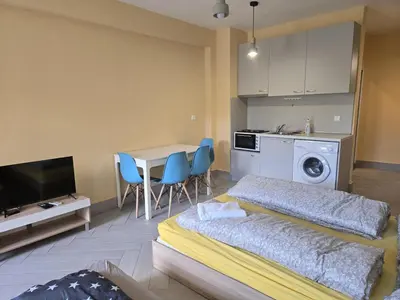 two beds in a room with a table and a kitchen at Green Oasis in Sofia