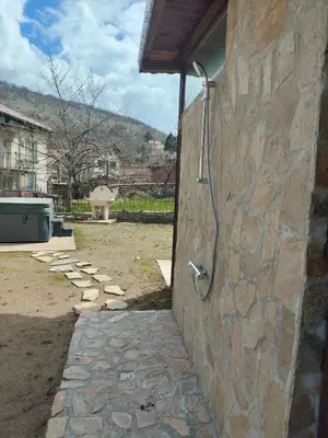 a stone wall with a shower in a yard at The Bird Villa in Bosnek