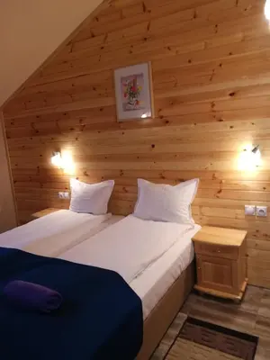 a bed in a room with a wooden wall at Guest House Edelweiss in Govedartsi