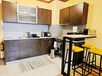 a kitchen with wooden cabinets and a counter top at Forest nest Cozy apartment white balcony on the hill in Bansko