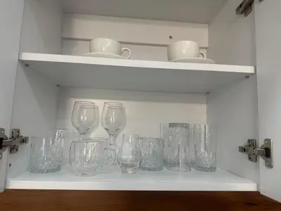a shelf filled with glass wine glasses on it at White lux in Sandanski