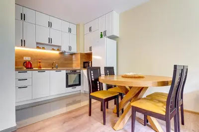 a kitchen and dining room with a wooden table and chairs at Forest Harmony 1BD with Balcony & Parking by Flat Manаger in Smolyan