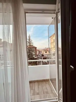 a balcony with a window and a view of a city at Unique flat with balcony in the heart of the city in Kyustendil