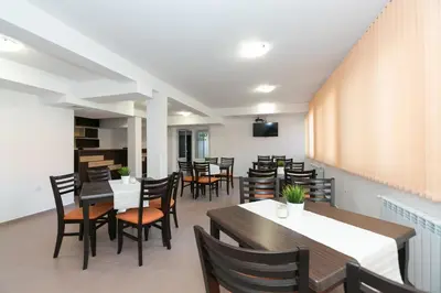 a dining room with tables and chairs and a television at Вилно селище Тракия- почивка сред природата in Tsigov Chark
