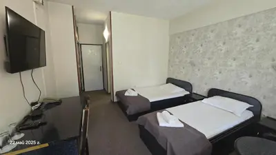 a hotel room with two beds and a flat screen tv at Хотел Тото Шанс in Velingrad