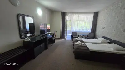 a hotel room with two beds and a television at Хотел Тото Шанс in Velingrad