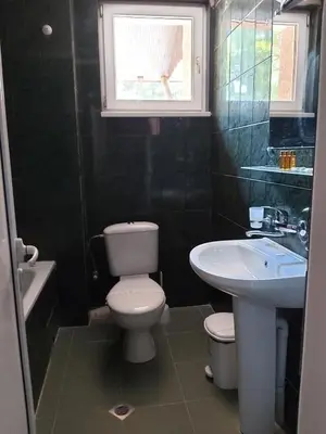 a bathroom with a toilet and a sink and a window at Хотел Тото Шанс in Velingrad