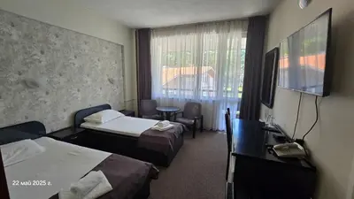 a hotel room with two beds and a television at Хотел Тото Шанс in Velingrad