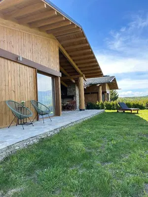 a house with a patio with two chairs and a table at Luxury Mountain Villa Pirin Golf K29H02 by Top Kvartiri Ltd in Razlog