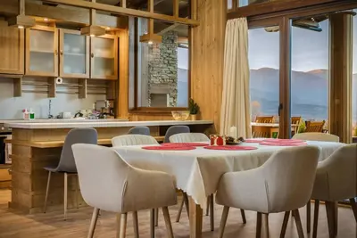 a dining room with a table and chairs and a kitchen at Pirin Golf Lux Villa for Ski & Chill by Top Kvartiri Ltd in Razlog