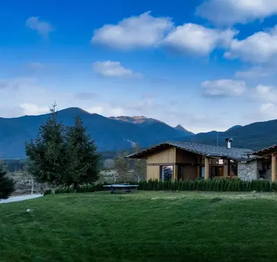 a house with a bench in a field with mountains at Pirin Golf Lux Villa for Ski & Chill by Top Kvartiri Ltd in Razlog
