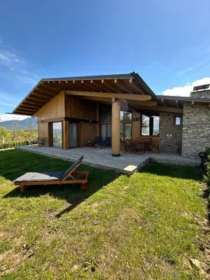 a house with a patio and a lounge chair in the grass at Pirin Golf Lux Villa for Ski & Chill by Top Kvartiri Ltd in Razlog