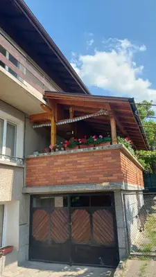 a building with a garage door with flowers on top at Бащината Къща in Sapareva Banya
