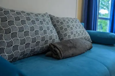 a blue couch with a pillow and two pillows on it at Comfy & Chic Apartment , SWU , FREE Parking in Blagoevgrad