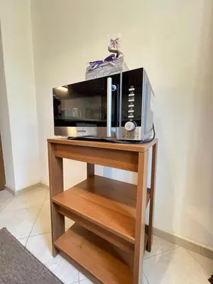 a microwave sitting on top of a wooden stand at Giza Cozy 1BDR w WiFi near Arena 8888 and SofiaMed in Sofia
