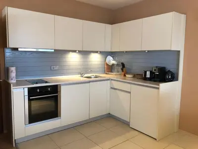 a kitchen with white cabinets and a sink at Panorama Apartment in Pamporovo