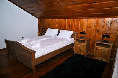 a bedroom with a bed with wooden walls and wooden floors at Къща Джано in Dobrinishte