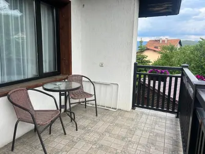 a patio with two chairs and a table on a balcony at Guest House Raffe in Dobrinishte