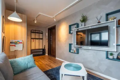 a living room with a couch and a tv on a wall at Leafy Loft in Sofia