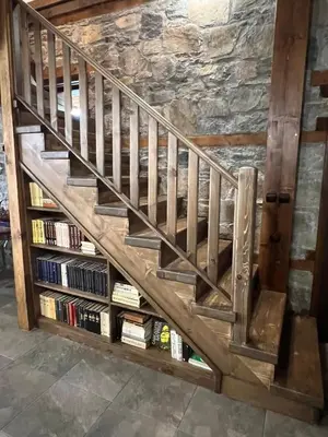a wooden staircase with a book shelf under it at Къща в Родопа планина in Leshten