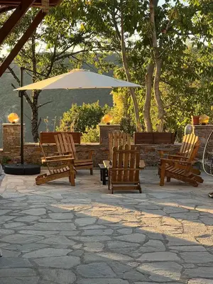 a group of chairs and an umbrella on a patio at Къща в Родопа планина in Leshten