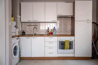 a kitchen with white cabinets and a washer and dryer at Center and Old Town Apartment in Plovdiv