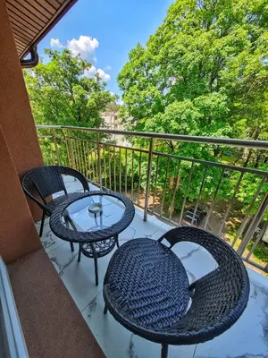 two tables and chairs on a balcony with trees at Апартамент Петя 2 in Velingrad