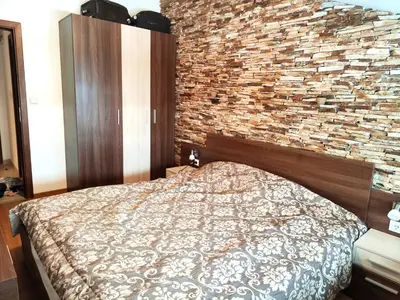a bedroom with a bed and a brick wall at Апартамент в Белведере Холидей клуб in Bansko
