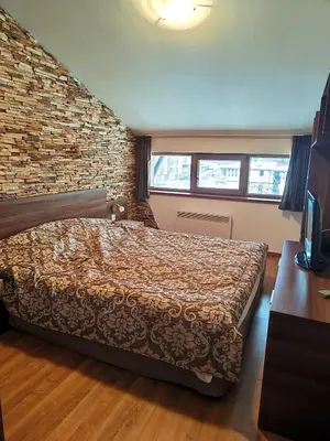 a bedroom with a bed and a brick wall at Апартамент в Белведере Холидей клуб in Bansko